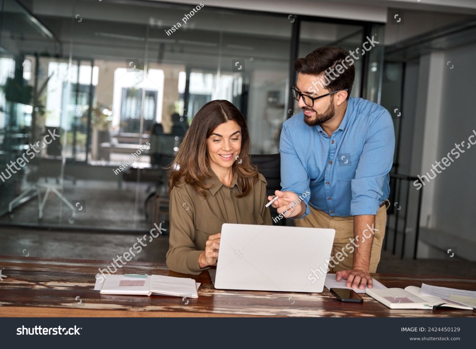 Two colleagues reviewing work on a laptop
