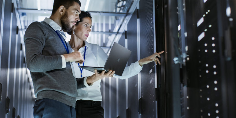 Two people looking at servers and checking status on laptop